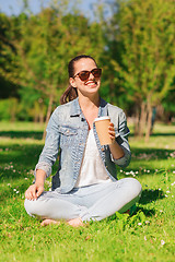 Image showing smiling young girl with cup of coffee in park
