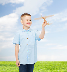 Image showing smiling little boy holding a wooden airplane model
