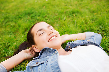 Image showing smiling young girl with closed eyes lying on grass