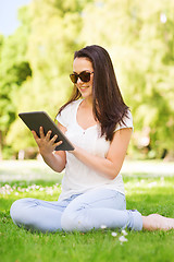 Image showing smiling young girl with tablet pc sitting on grass