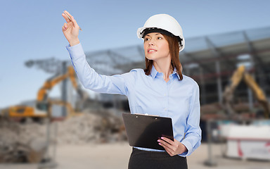 Image showing smiling businesswoman in helmet with clipboard