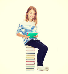 Image showing little student girl sitting on stack of books