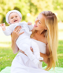 Image showing happy mother with little baby sitting on blanket