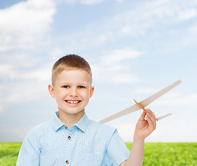Image showing smiling little boy holding a wooden airplane model