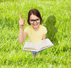 Image showing smiling little girl in eyeglasses with book