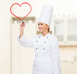 Image showing smiling female chef writing something on air