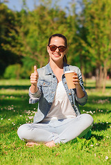 Image showing smiling young girl with cup of coffee in park