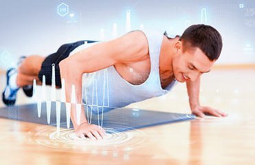 Image showing smiling man doing push-ups in the gym