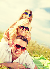 Image showing smiling family in sunglasses lying on blanket