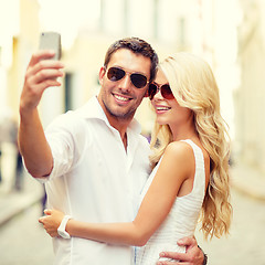 Image showing smiling couple taking selfie with smartphone