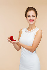 Image showing smiling woman holding red gift box with ring