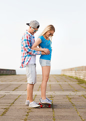 Image showing smiling couple with skateboard outdoors