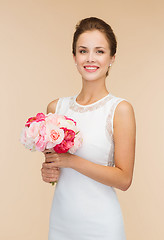 Image showing smiling woman in white dress with bouquet of roses