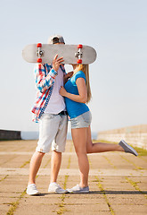 Image showing couple with skateboard kissing outdoors