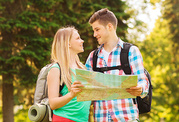 Image showing smiling couple with map and backpacks in forest