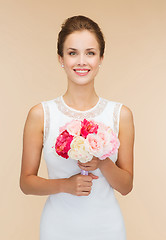 Image showing smiling woman in white dress with bouquet of roses