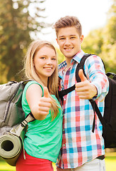 Image showing smiling couple with backpacks showing thumbs up