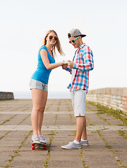 Image showing smiling couple with skateboard outdoors