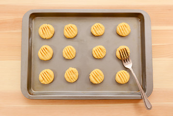 Image showing Flattening balls of biscuit dough on a tray