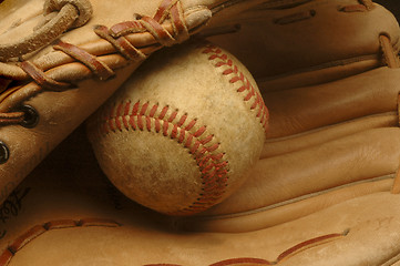 Image showing Well-used baseball nestled in a glove.