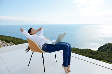 Image showing relaxed young woman at home working on laptop