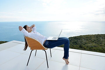 Image showing relaxed young woman at home working on laptop