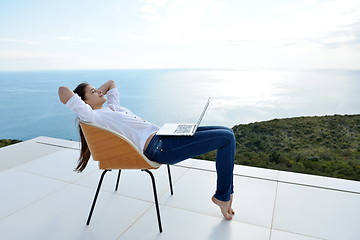 Image showing relaxed young woman at home working on laptop