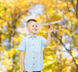 Image showing smiling little boy holding a wooden airplane model