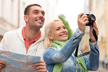 Image showing smiling couple with map and photocamera in city