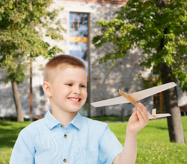 Image showing smiling little boy holding a wooden airplane model