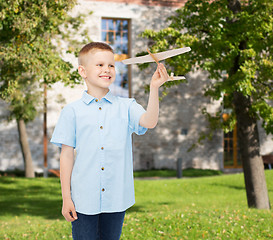 Image showing smiling little boy holding a wooden airplane model