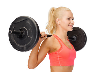 Image showing smiling sporty woman exercising with barbell