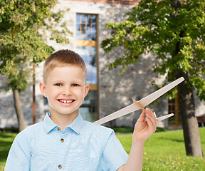 Image showing smiling little boy holding a wooden airplane model