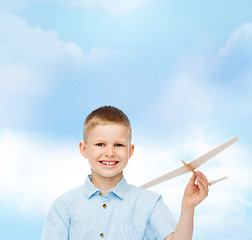 Image showing smiling little boy holding a wooden airplane model