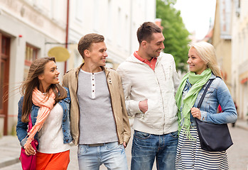 Image showing group of smiling friends walking in the city