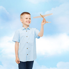 Image showing smiling little boy holding a wooden airplane model