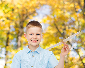 Image showing smiling little boy holding a wooden airplane model