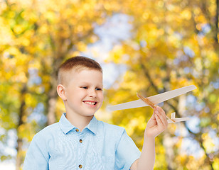 Image showing smiling little boy holding a wooden airplane model