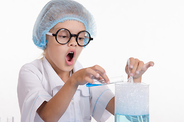 Image showing Chemist pours blue liquid in the flask