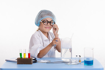 Image showing Chemist pours the blue liquid in flask