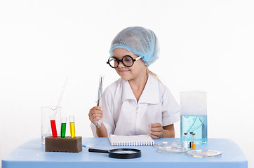 Image showing Girl chemist holding tweezers