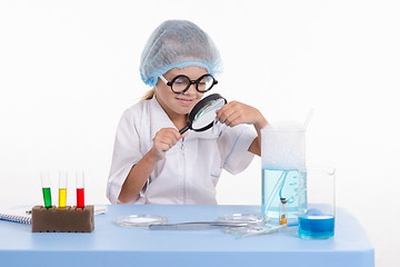 Image showing Chemist looking through a magnifying glass on white powder