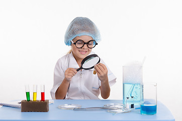 Image showing Chemist looking through a magnifying glass on powder