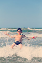 Image showing Happy boy running and jumping at shallow sea water