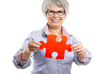 Image showing Elderly woman holding a puzzle piece