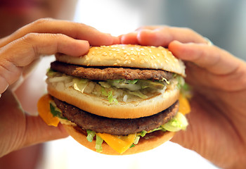 Image showing man's hands, holding onto a burger