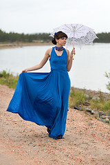 Image showing Young slim girl in a blue dress with an umbrella