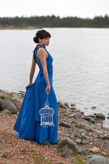 Image showing girl in a blue dress with an empty bird cage