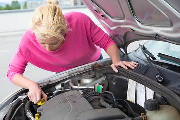 Image showing Woman inspecting broken car engine.