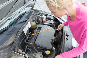 Image showing Woman inspecting broken car engine.